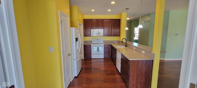 kitchen with decorative light fixtures, a sink, light stone countertops, white appliances, and a peninsula