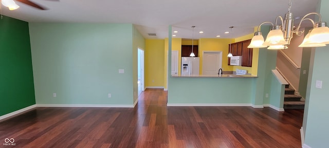 kitchen featuring white appliances, baseboards, dark wood-style flooring, a peninsula, and pendant lighting