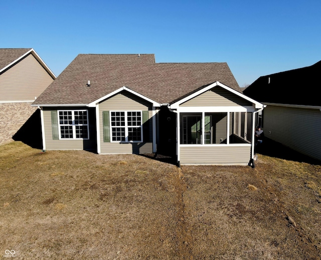 back of house with a sunroom, roof with shingles, and a yard