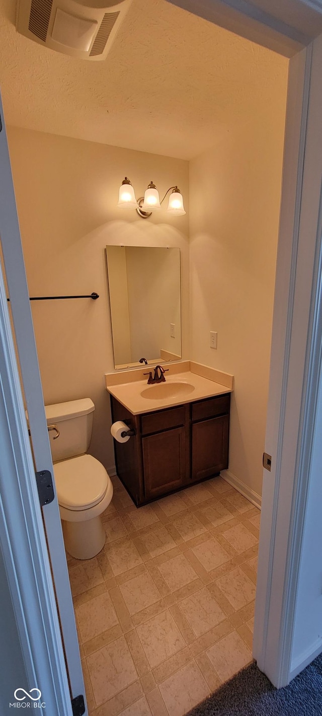 bathroom with visible vents, toilet, vanity, baseboards, and tile patterned floors