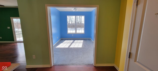 doorway featuring baseboards and wood finished floors