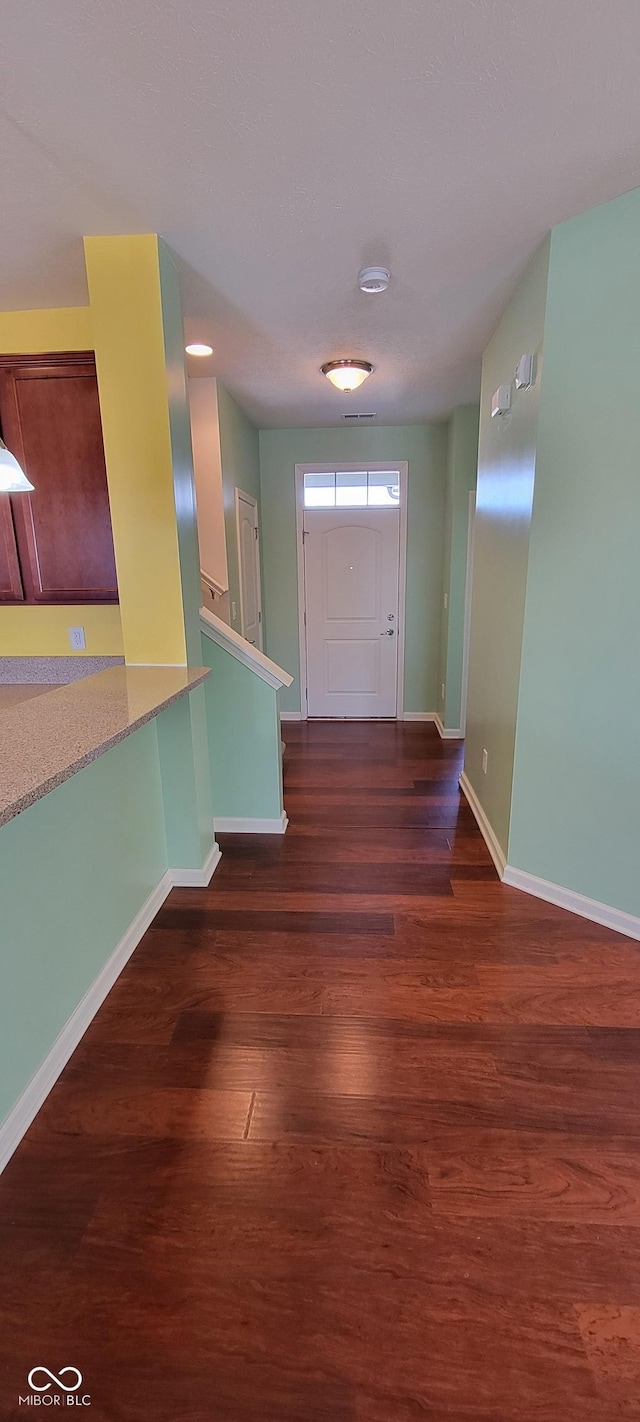 foyer entrance featuring dark wood-style flooring and baseboards