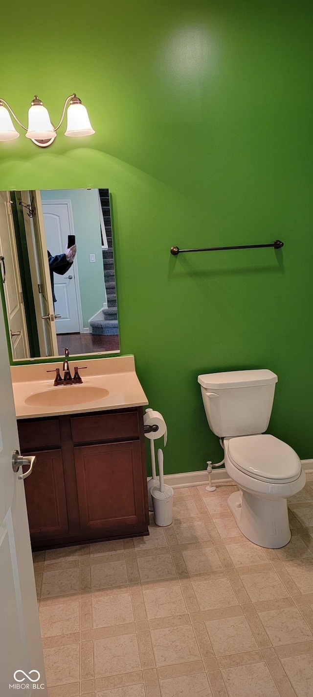 half bathroom with toilet, baseboards, and vanity