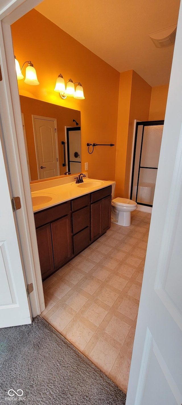 bathroom with double vanity, an enclosed shower, toilet, and a sink