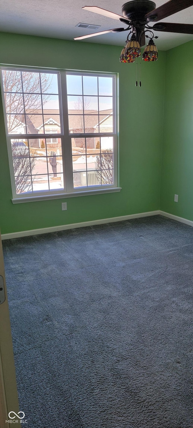 empty room featuring visible vents, carpet, a ceiling fan, and baseboards