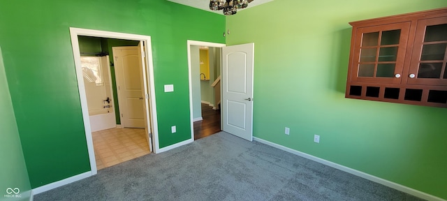 unfurnished bedroom featuring baseboards, a chandelier, and light colored carpet