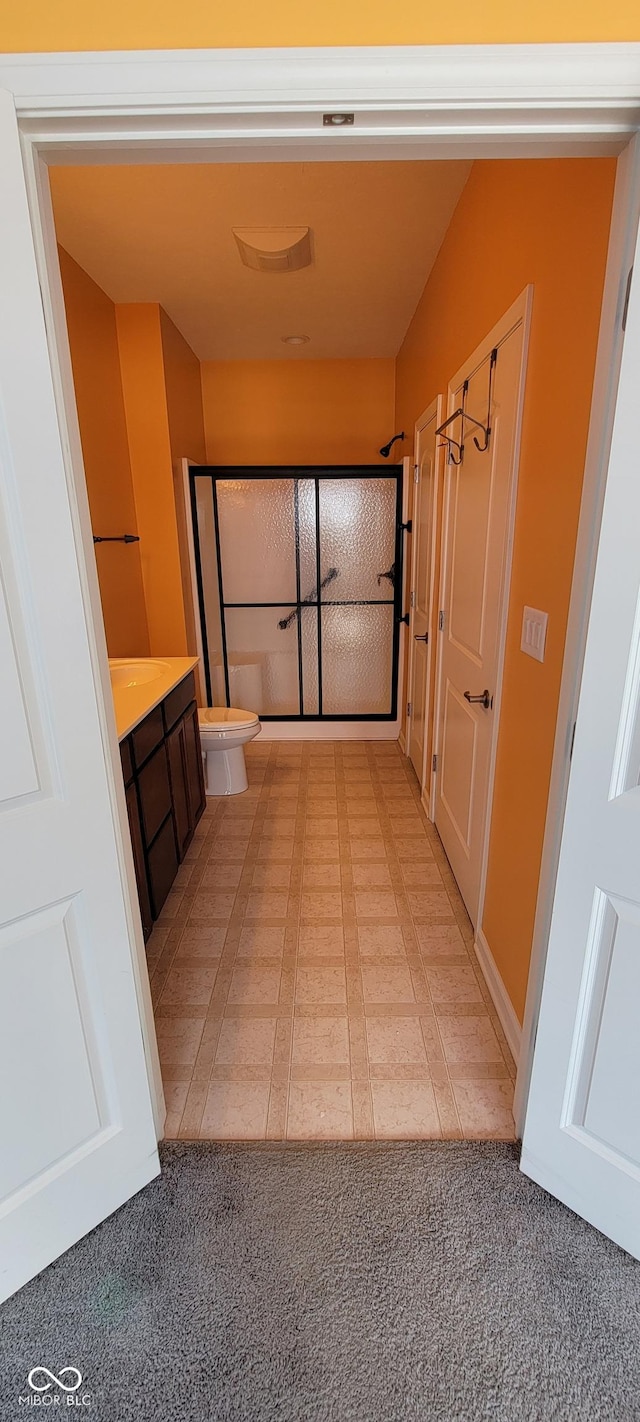 full bath featuring toilet, a shower with shower door, and vanity