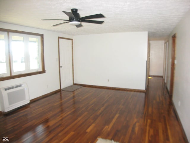 unfurnished room with a textured ceiling, a wall unit AC, a ceiling fan, baseboards, and dark wood finished floors