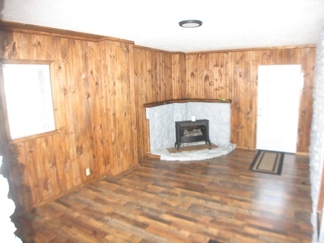 unfurnished living room with a wood stove, wood walls, and dark wood-style flooring