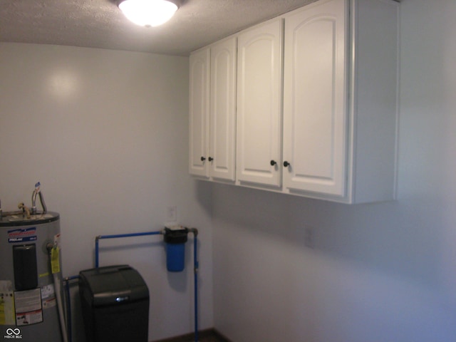 washroom featuring electric water heater and a textured ceiling