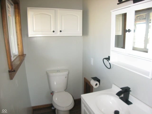 half bath featuring a sink, toilet, and baseboards