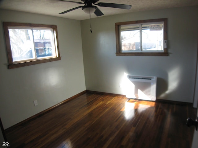 unfurnished room featuring dark wood-style floors, radiator heating unit, ceiling fan, a textured ceiling, and baseboards