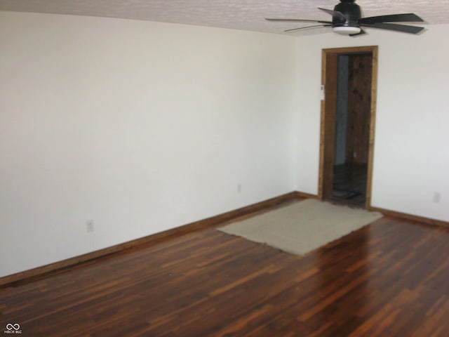 spare room with dark wood-style floors, ceiling fan, a textured ceiling, and baseboards