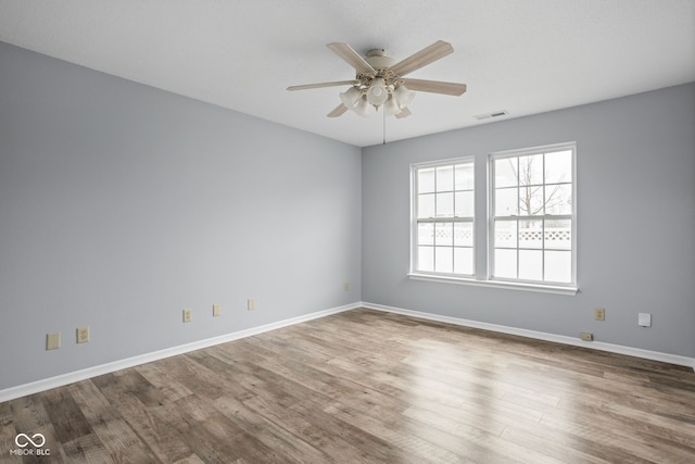 unfurnished room featuring a ceiling fan, baseboards, visible vents, and wood finished floors