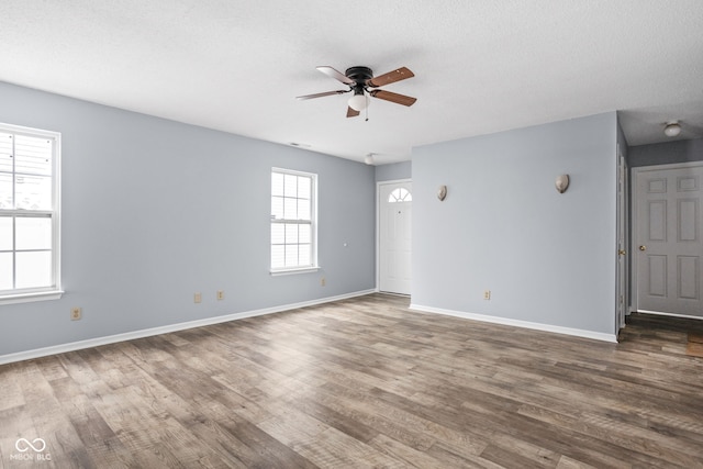 spare room with a ceiling fan, a textured ceiling, baseboards, and wood finished floors