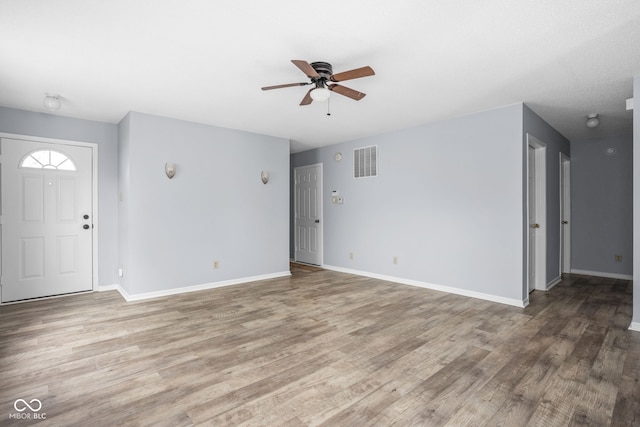 unfurnished living room featuring wood finished floors, visible vents, and baseboards