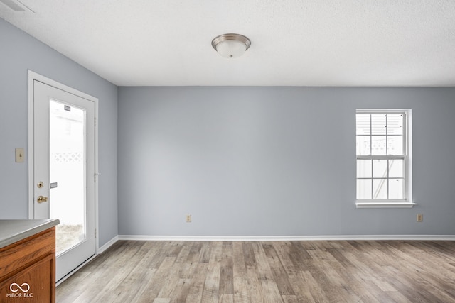 empty room with light wood-type flooring, visible vents, and baseboards