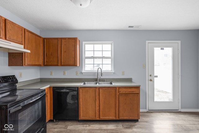 kitchen with under cabinet range hood, a sink, visible vents, a healthy amount of sunlight, and black appliances