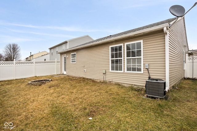 back of property with a fenced backyard, central AC, and a yard