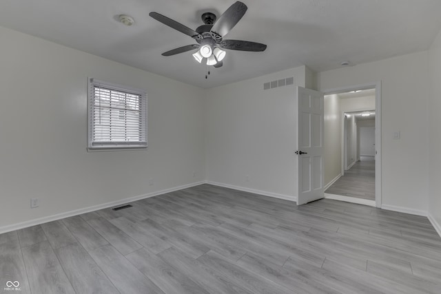 empty room with light wood finished floors, baseboards, and visible vents