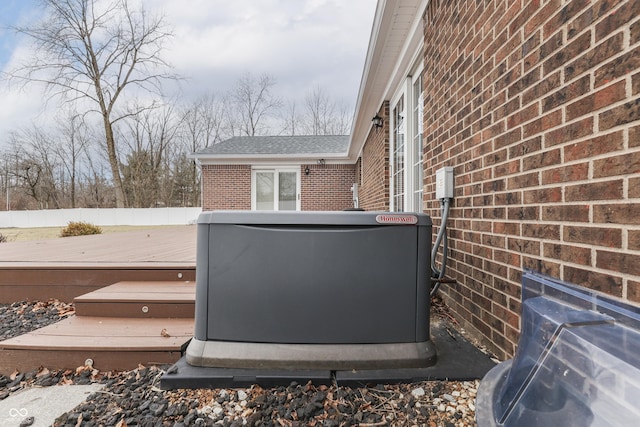 exterior details with a power unit, brick siding, fence, and a wood stove