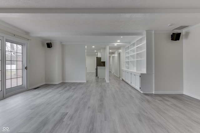 unfurnished living room featuring light wood-style floors, beam ceiling, visible vents, and baseboards