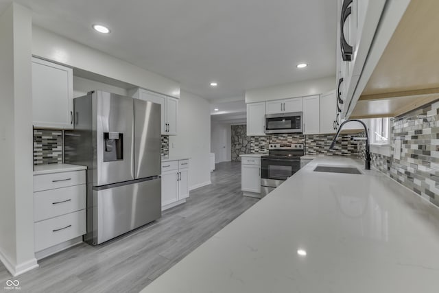 kitchen with stainless steel appliances, tasteful backsplash, a sink, and white cabinets