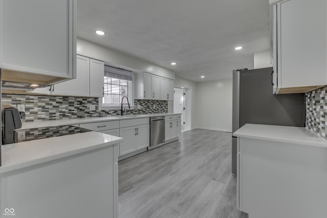 kitchen with light countertops, stainless steel dishwasher, white cabinets, a sink, and range