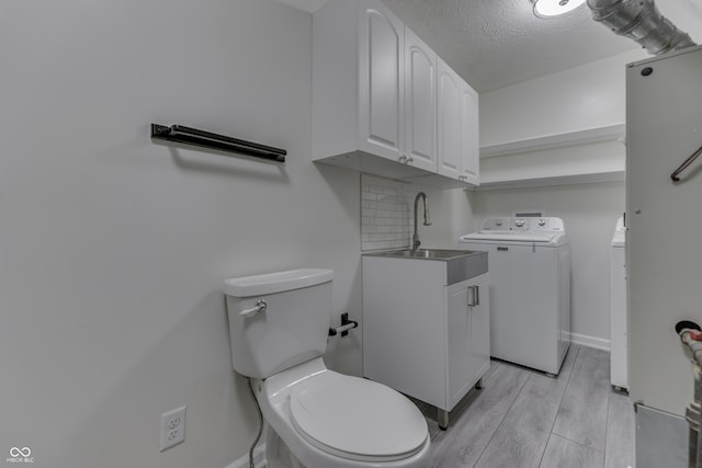 bathroom with toilet, wood finish floors, a sink, baseboards, and backsplash