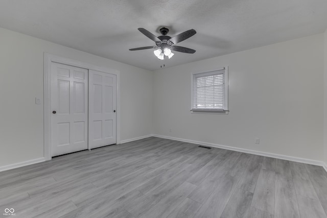 unfurnished bedroom featuring light wood-style flooring, a closet, visible vents, and baseboards