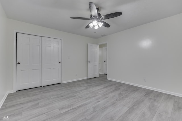 unfurnished bedroom featuring a ceiling fan, a closet, light wood-style flooring, and baseboards