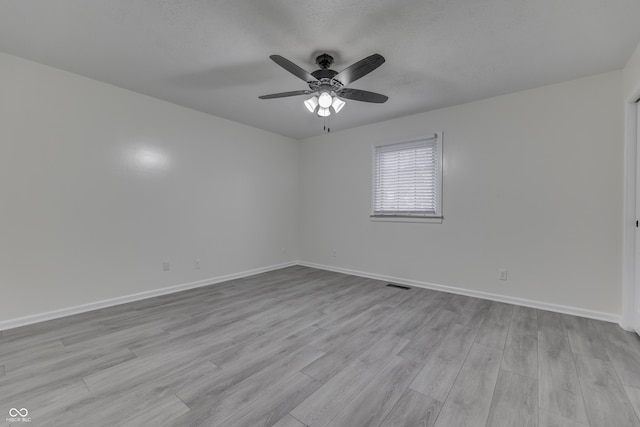 empty room with light wood-type flooring, visible vents, ceiling fan, and baseboards