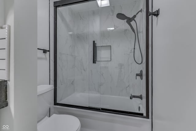 bathroom with combined bath / shower with glass door and toilet