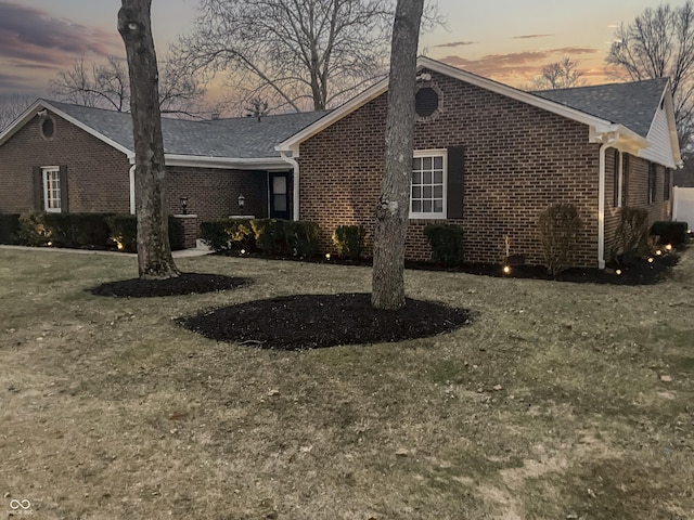 view of front facade featuring brick siding and a lawn