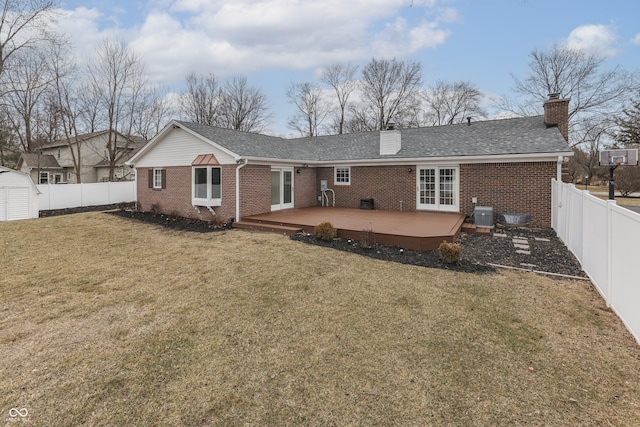 rear view of house featuring brick siding, a chimney, a lawn, a fenced backyard, and a wooden deck