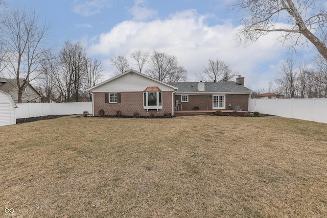 back of property with a fenced backyard, brick siding, a chimney, and a lawn