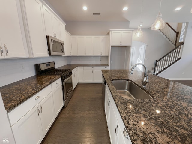 kitchen featuring stainless steel appliances, white cabinetry, a sink, and visible vents