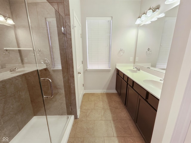 full bath with double vanity, a stall shower, baseboards, and a sink