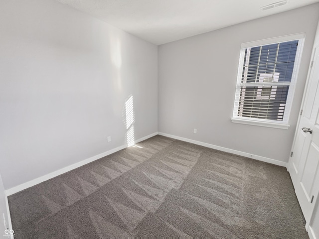 spare room featuring a wealth of natural light, carpet, visible vents, and baseboards