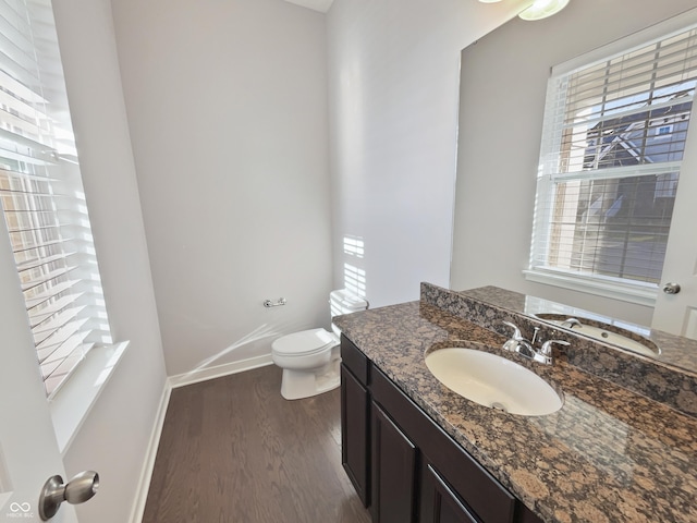 bathroom featuring toilet, wood finished floors, a wealth of natural light, and baseboards