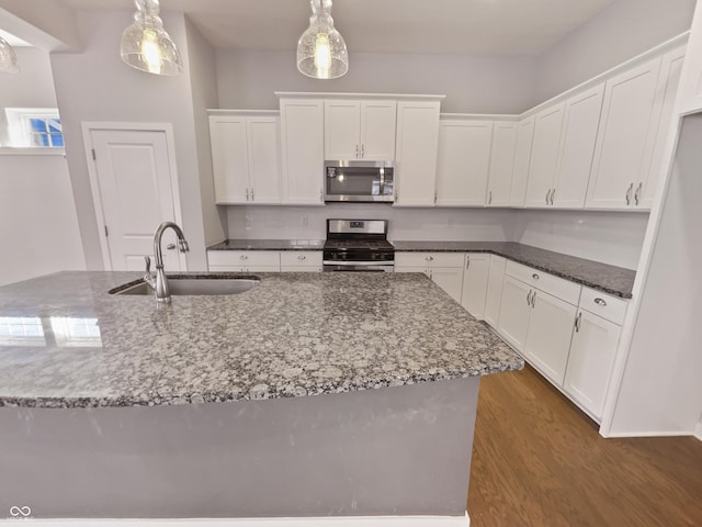 kitchen with stainless steel appliances, dark wood-style flooring, a sink, and white cabinetry