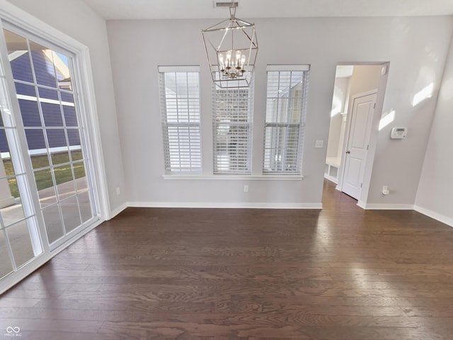 unfurnished dining area featuring an inviting chandelier, dark wood finished floors, and baseboards