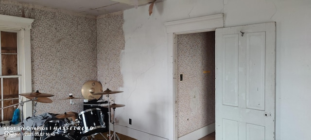 misc room featuring wallpapered walls and baseboards