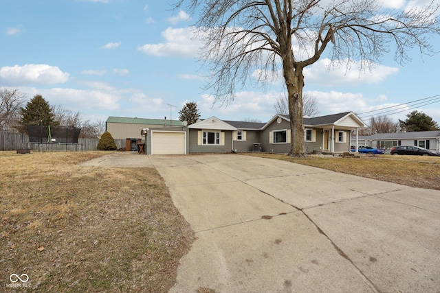 single story home featuring an attached garage, fence, driveway, a trampoline, and a front yard