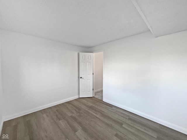 spare room with baseboards and wood finished floors