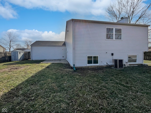 back of house featuring a storage unit, a lawn, central AC unit, and fence