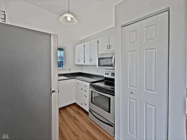 kitchen with decorative light fixtures, stainless steel appliances, dark countertops, white cabinetry, and wood finished floors