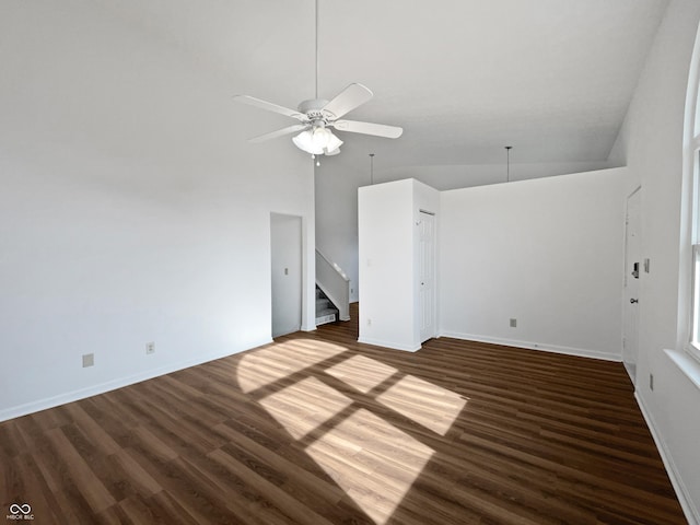 interior space with a ceiling fan, baseboards, a high ceiling, and wood finished floors