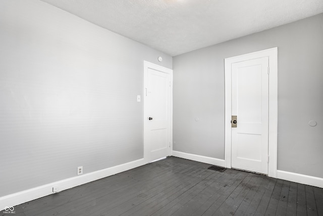 empty room featuring baseboards, a textured ceiling, and dark wood-style floors