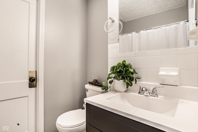 bathroom with curtained shower, toilet, vanity, a textured ceiling, and tile walls